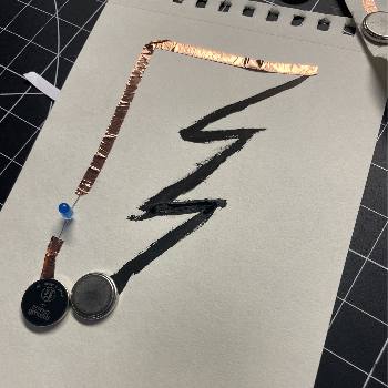 This was another circuit I made with Saksham and it conducted through the black paint. We placed the tape around the paint shaped like a lightning bolt whcih allowed the leds to light up when the battery was connected.